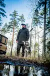 Jäger steht mit Hund in einem Wald neben einem Geländewagen