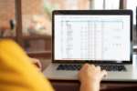 Laptop zeigt eine Finanzübersicht in TRIMIT mit Geschäftsdaten, Konten und Kennzahlen für das Finanzmanagement.